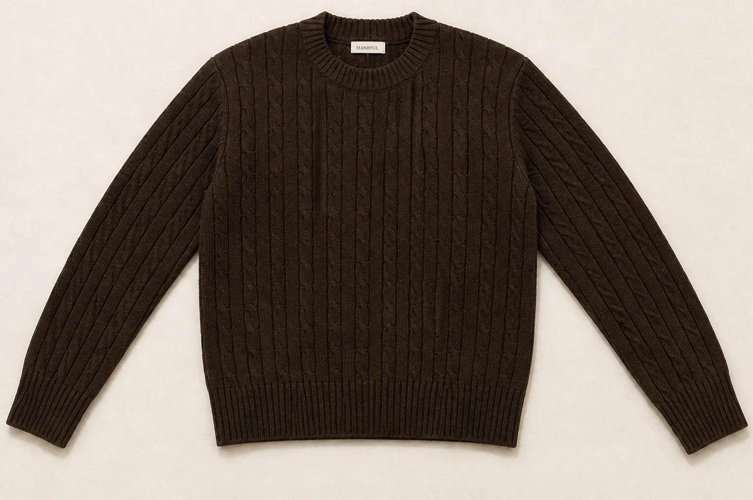 Clean flat-lay product master of the dark chocolate cable knit on a warm neutral background