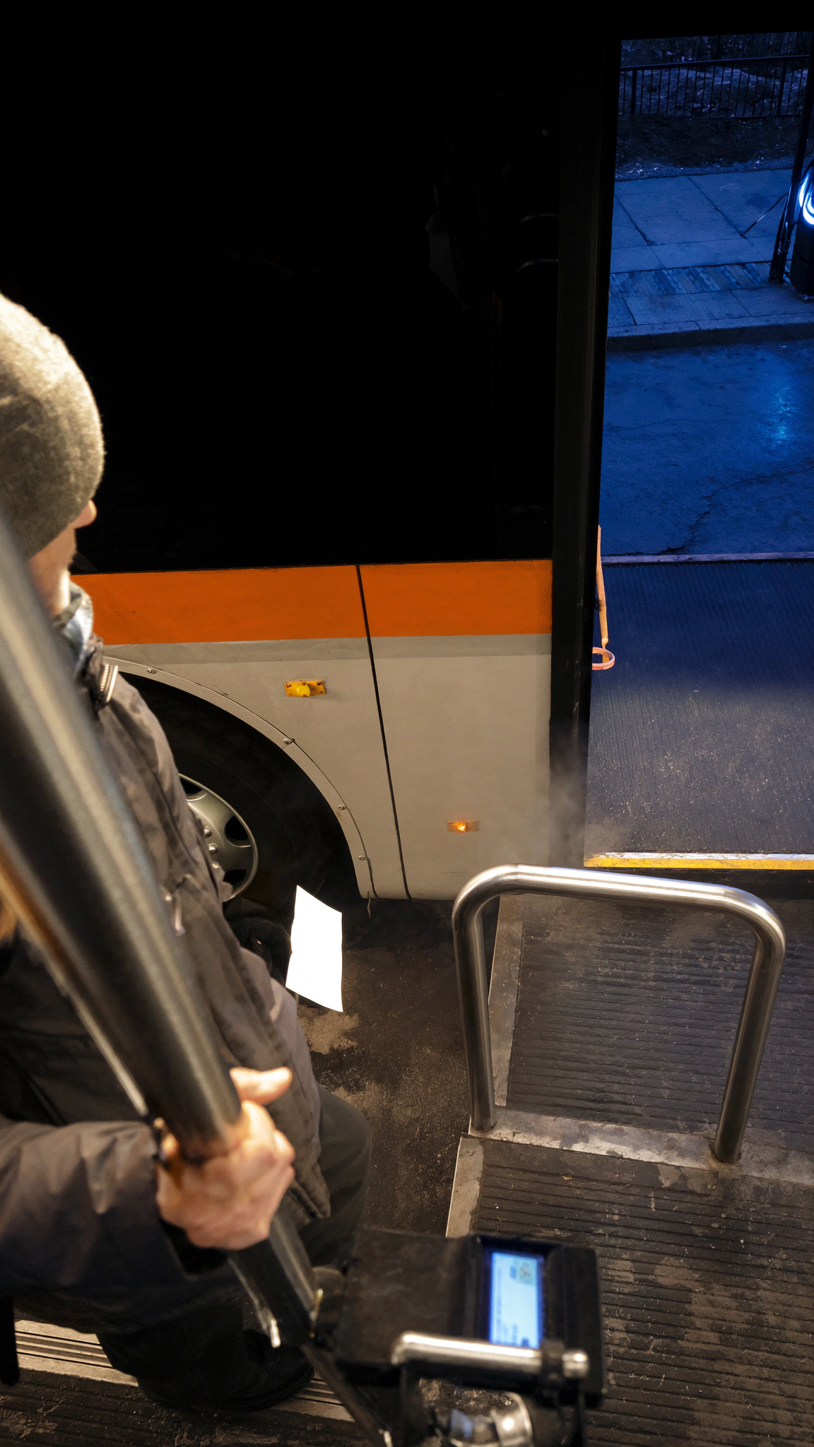 An early commuter walks toward the coach at a blue-hour regional terminal.