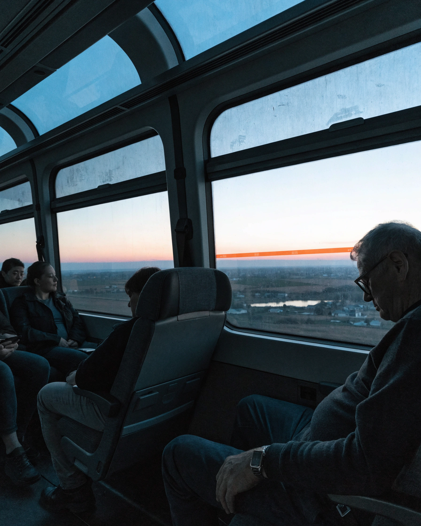 Passengers face a wide regional landscape through the quiet coach interior.
