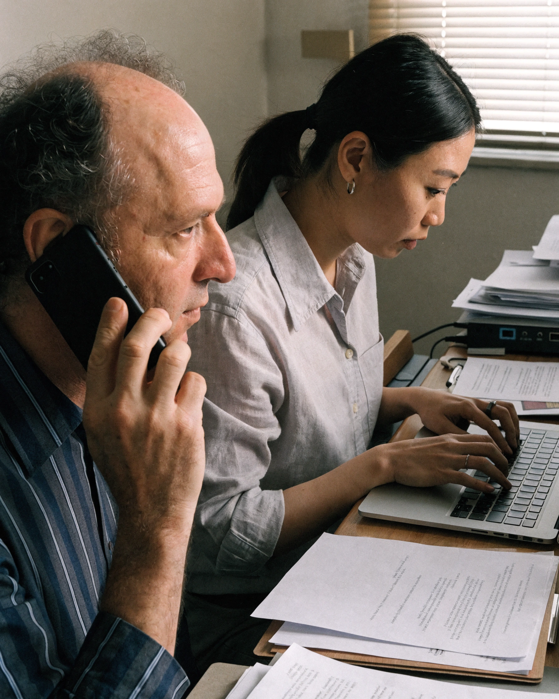 A researcher confirms a detail by phone while the relevant document stays open.