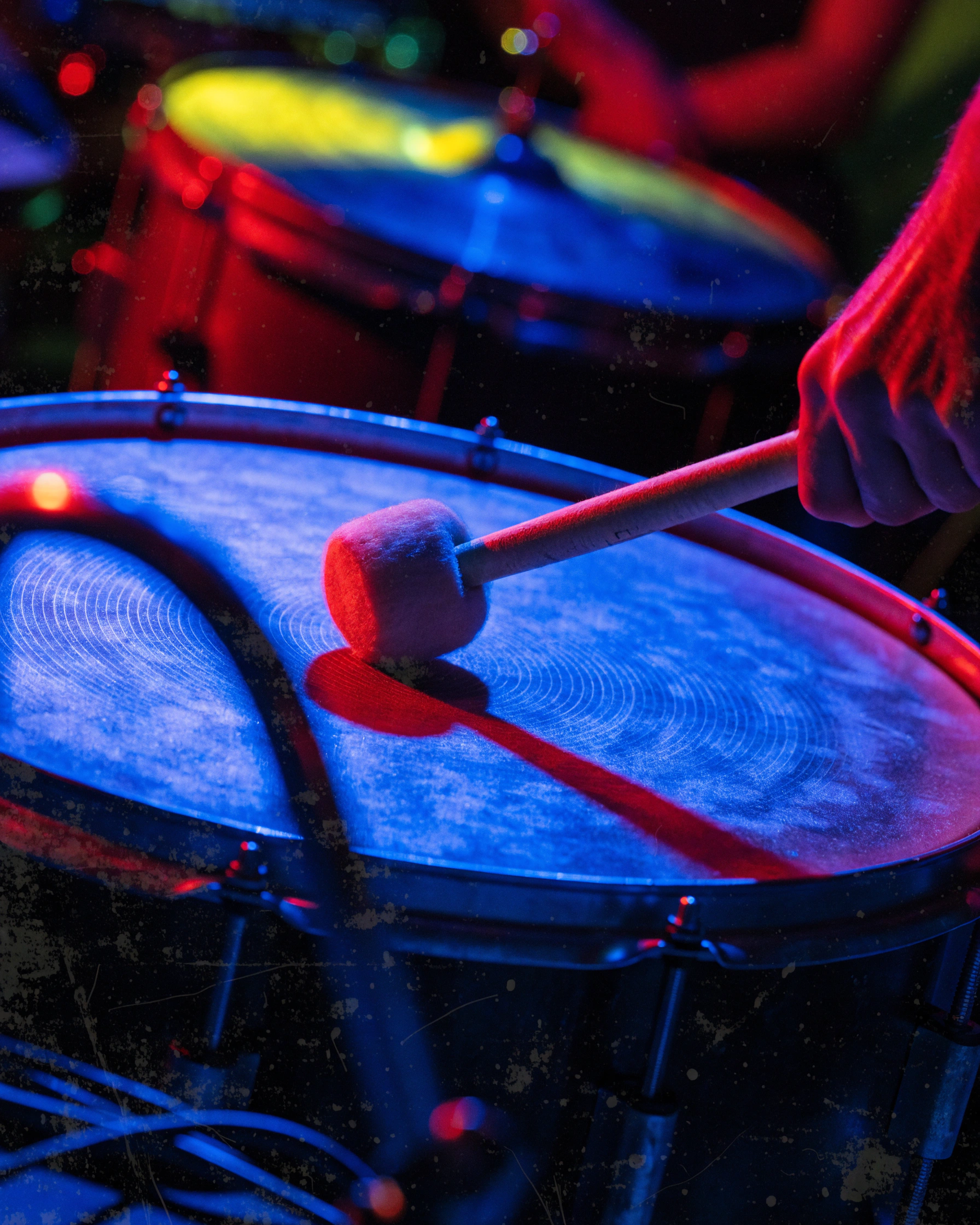 A drum membrane flexes under a mallet at the instant of contact.
