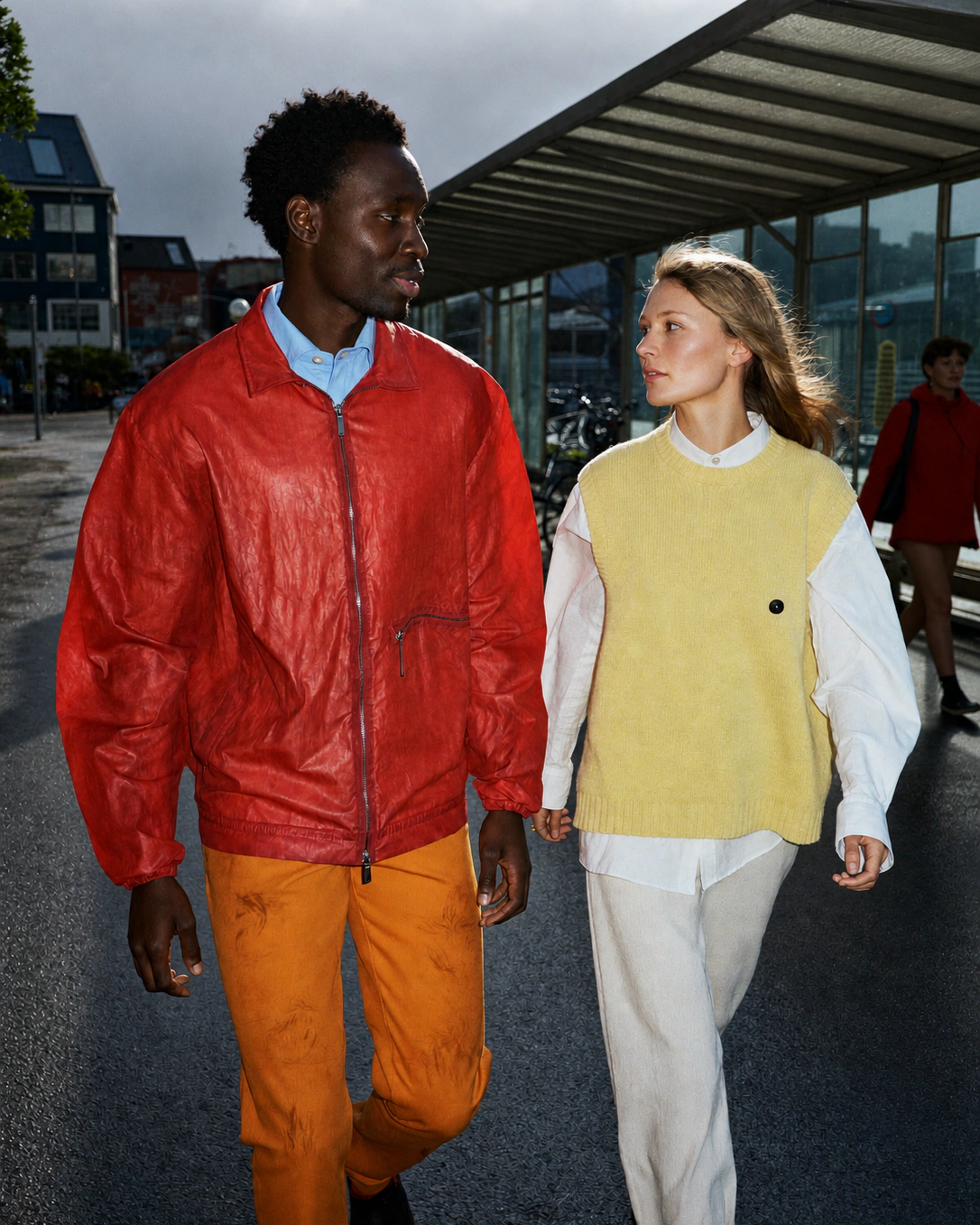 Two people walking past a bus stop in an urban fashion campaign.