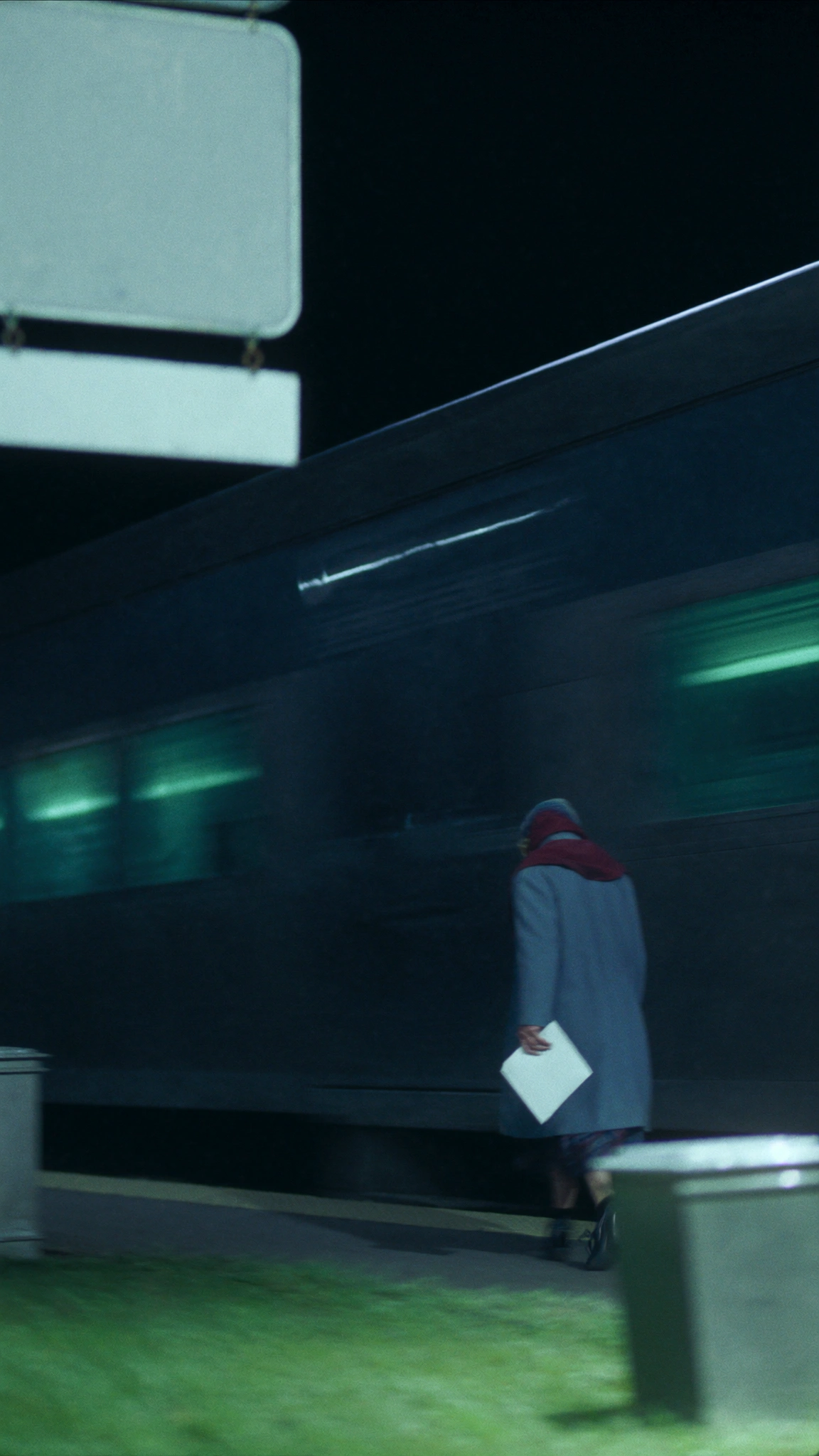 A passenger holds the sealed envelope beside a dark train window.
