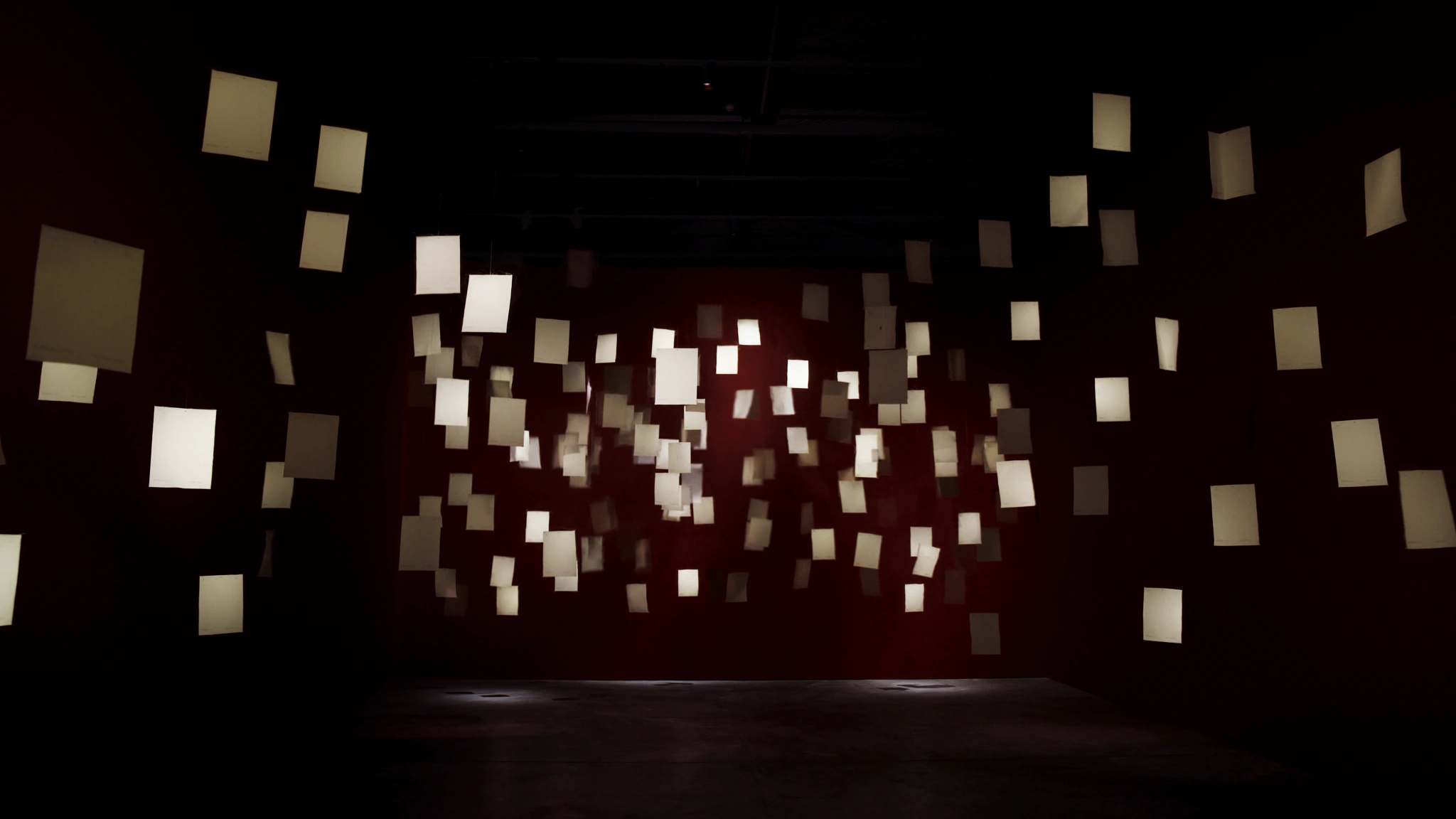Suspended correspondence sheets form a restrained literary installation.