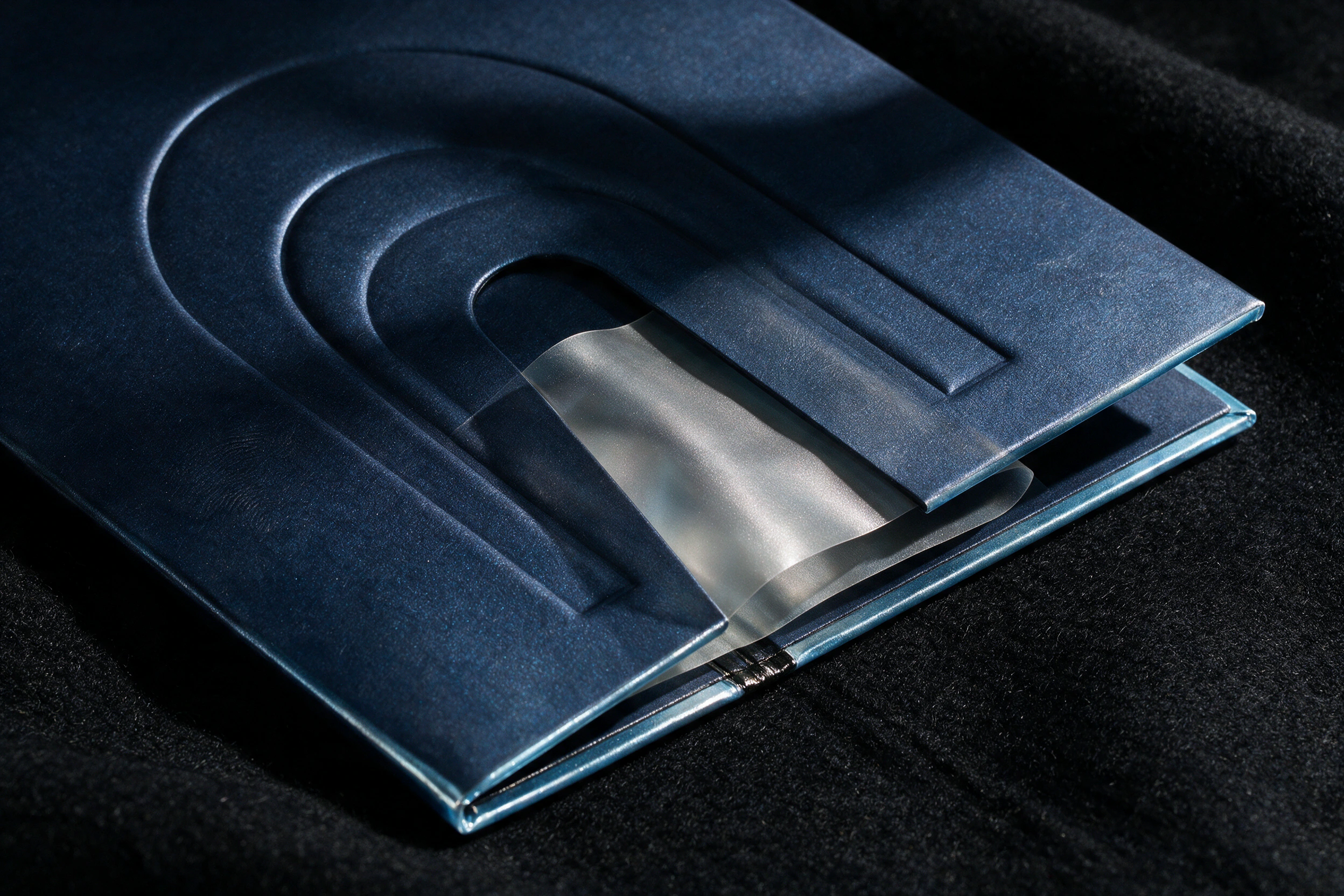 Pearlescent stock, black foil, gloss photography, and a translucent sleeve form the issue.