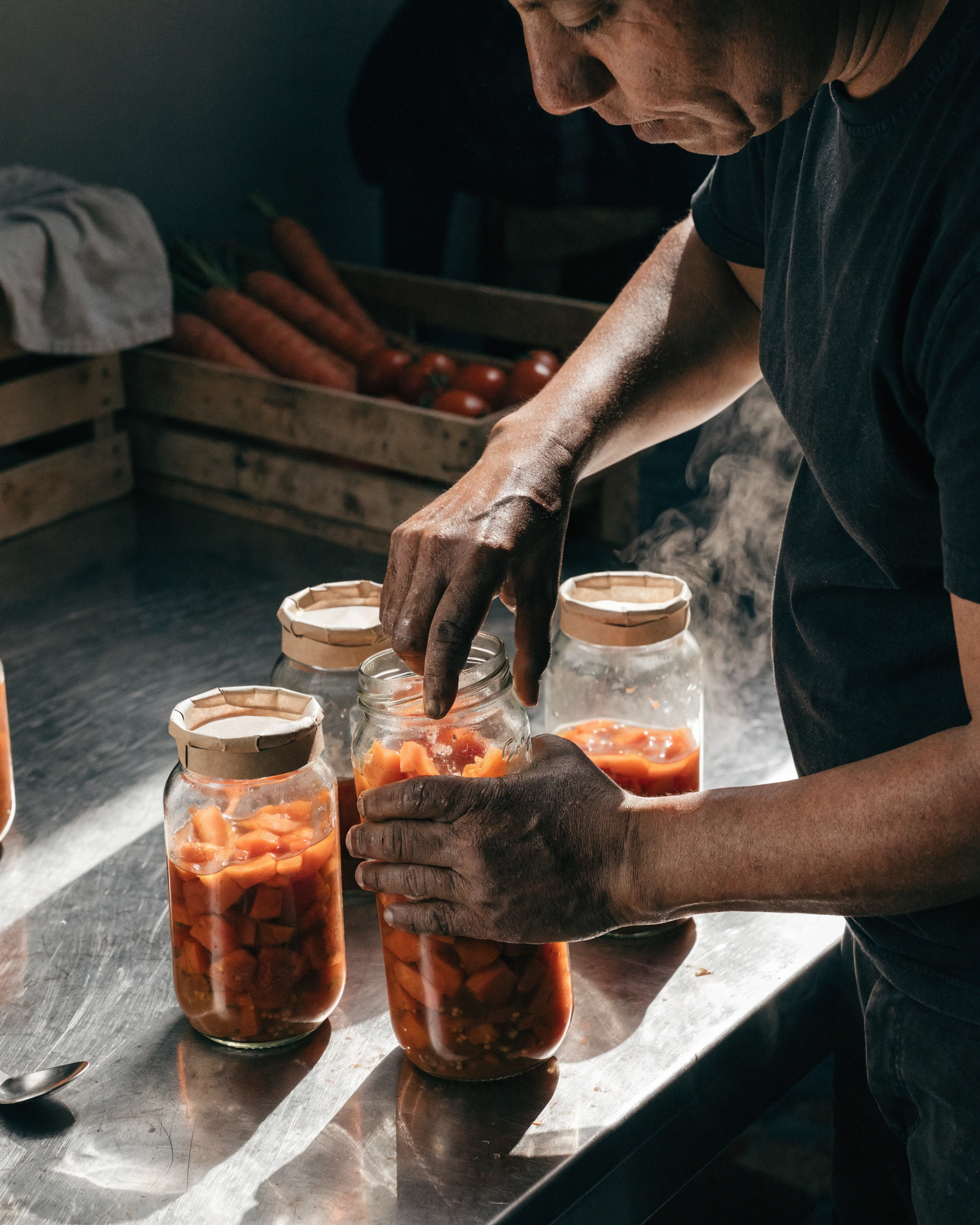 A cook fills returnable jars while the source crate remains visible behind the bench.