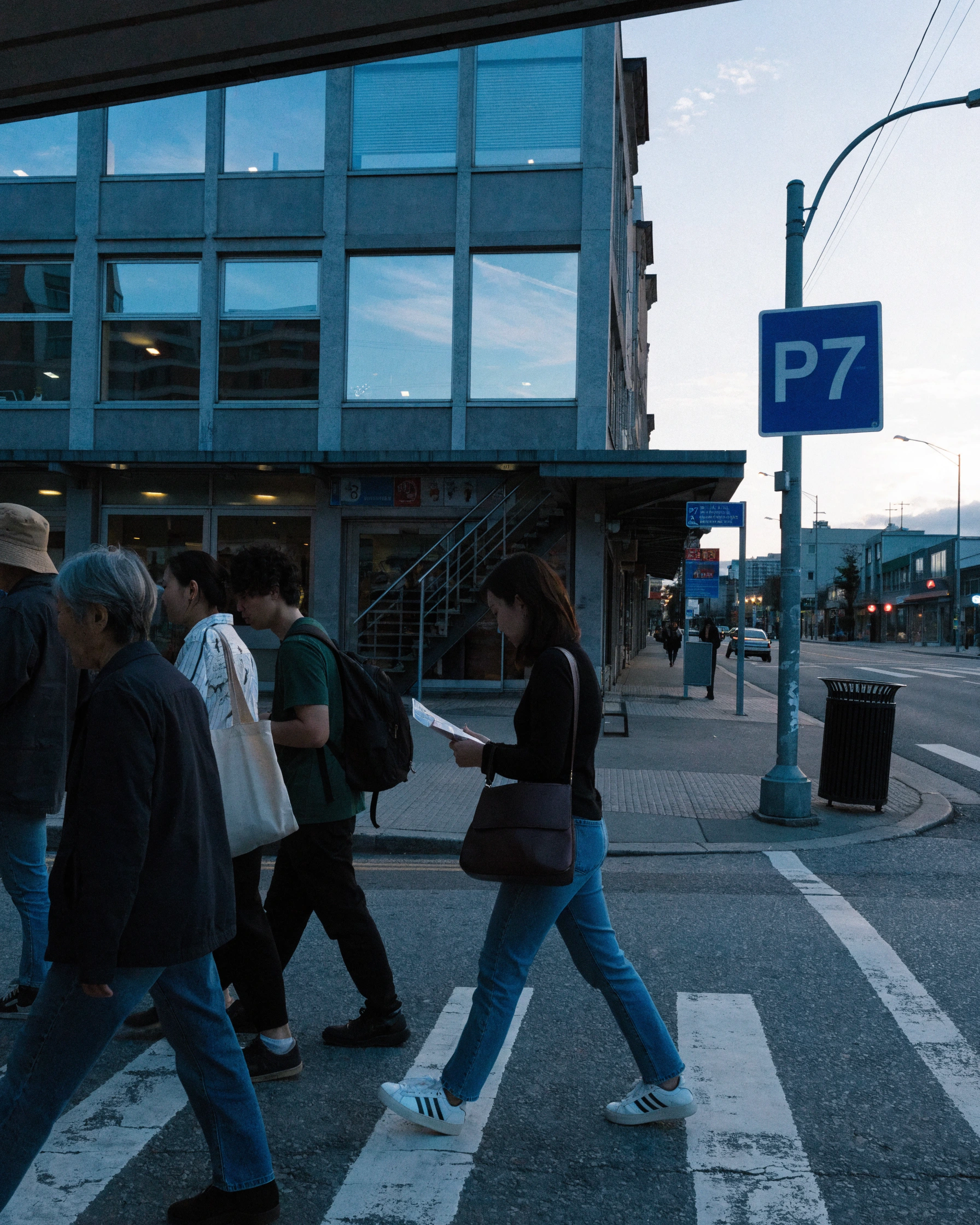 Residents cross an intersection while the route marker stays visible behind them.