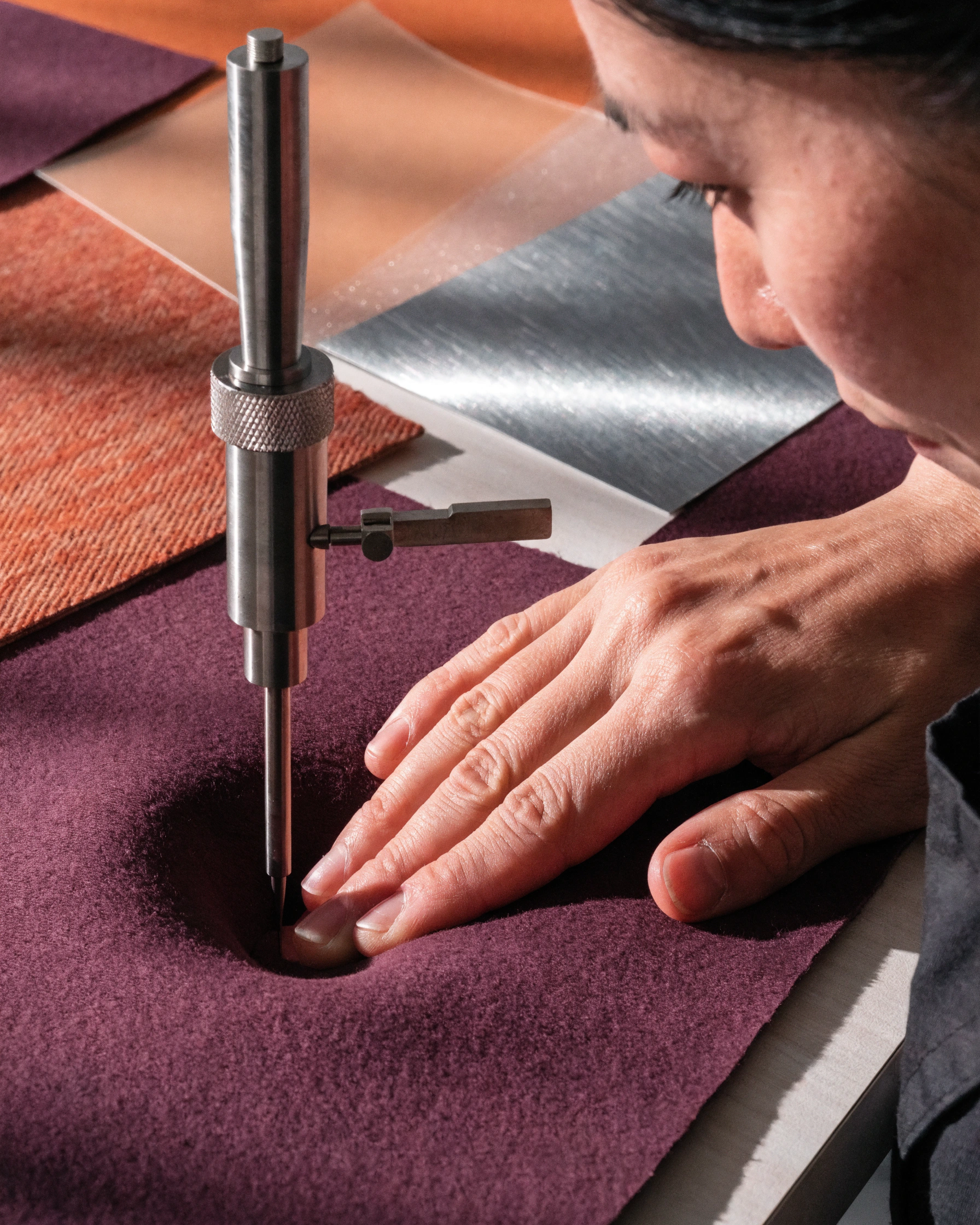 A fingertip depresses a soft sample while a depth gauge records the change.